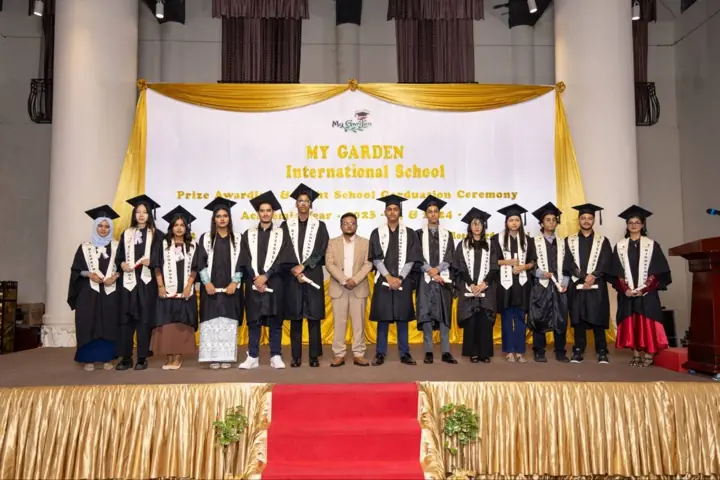 Graduates in caps and gowns on stage at the My Garden graduation ceremony
